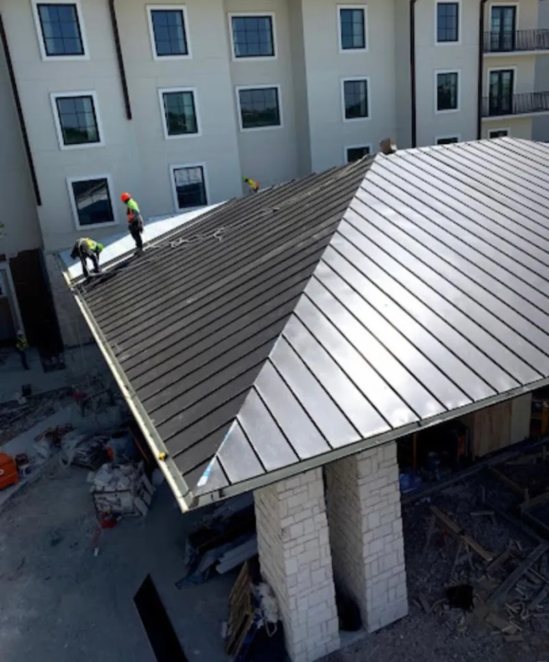 Crew installing standing seam metal roof panels on a commercial project in River Ridge